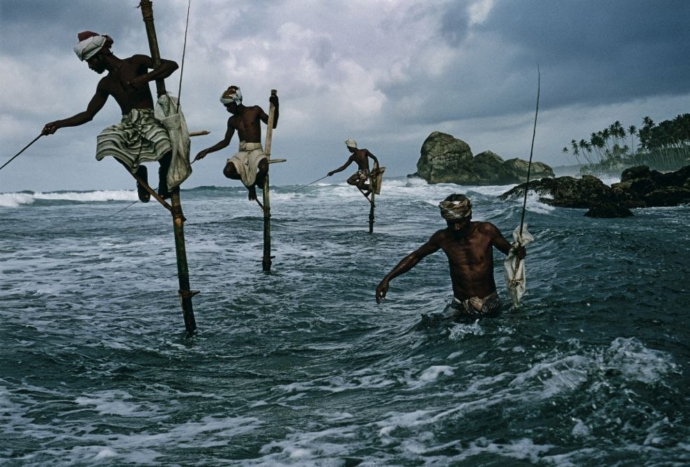 Fishermen catch spotted herring sitting on wooden stands. - The national geographic, The photo, Fishermen